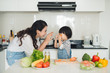 © makistock - Happy family in the kitchen. Mother and child daughter are preparing the vegetables and fruit.