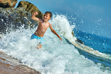 Cute Caucasian boy in sea waves.