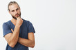 © Cookie Studio - Portrait of attractive young man with stylish hairstyle holding hand on chin with thoughtful expression, looking in camera. Guy thinking about future life.