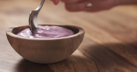 Wall Mural - young female hand eating blueberry yogurt with spoon