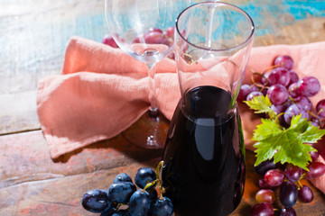 Small carafe with dry red wine, two wine glasses and grapes