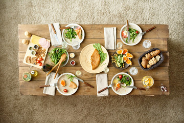 Above view of wooden dinner table with half-eaten dishes left on it, no people