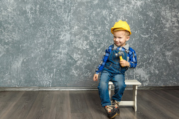 Wall Mural - the boy in yellow hard hat holding a hammer