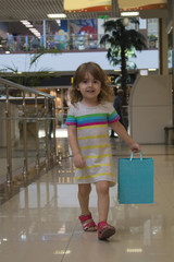 cute little girl is walking along a supermarket with a color package