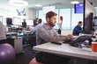 © wavebreak3 - Young businessman working at desk while sitting on exercise ball
