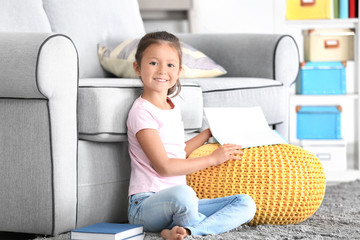 Cute little girl reading book at home