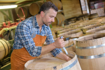 wood barrels production cooper using hammer and tools in workshop