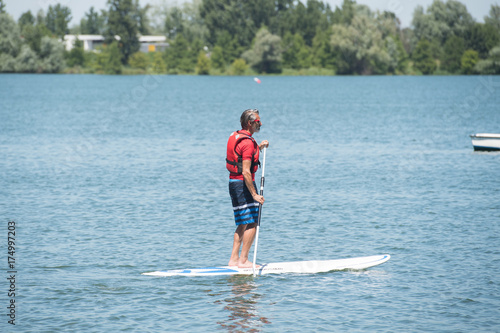 Zdjęcie XXL człowiek, ciesząc się jazdą po jeziorze z paddleboard