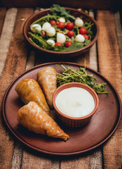 Wall Mural - Tasty meat rolls with sour cream and salad on wooden table