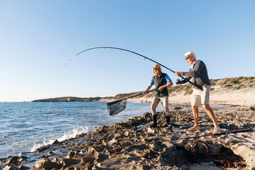 Wall Mural - Senior man fishing with his grandson