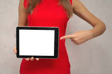 Young Woman In Red Dress Holding In Hands Tablet Computer With Blank Screen And Pointing On It By Finger. Product Presentation. Special Offer.