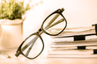 Close up black reading eyeglasses on stacking of office paper , the business working document and information data concept. retro color tone