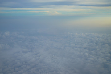 Wall Mural - view of dreamy abstract white cloud with blue sky and sunrise light background from airplane window