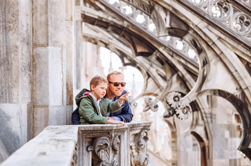 father with son tourists are on the roof of milan cathedral