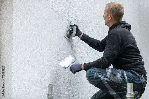 Fotografía construction worker putting decorative plaster on house exterior