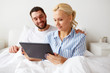 © Syda Productions - smiling happy couple with tablet pc in bed at home