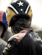 Rear View Of Man Wearing Yellow And Blue Crash Helmet And Black Leather Jacket.