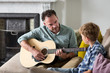 © ReeldealHD images - Father teaching son how to play guitar