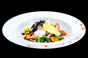 Sticker - Tasty, delicious salad with baked pumpkin in a white plate isolated on black background. Autumn menu in an Italian restaurant