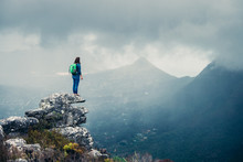 Female Hiker On A Rocky Outcrop Overlooking A Stormy Mountain View