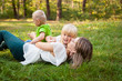 © justesfir - Family concept, mother playing with her kids and kissing her daughter on the grass