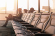 © jack-sooksan - Leather chairs with blurry unknown passengers waiting flight at gate of airport in morning.