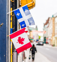 Closeup Of Two Small Canadian And Quebec Flags Hanging On Restaurant On Saint Louis Street In Old Town Road