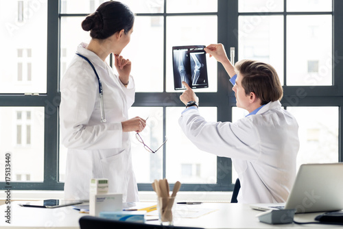 Cuadros en Lienzo Experienced male orthopedist helping his female colleague with the interpretatio