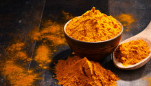 Composition With Bowl Of Turmeric Powder On Wooden Table