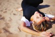 © raisondtre - Young slim pretty girl in a black dress and white bolero with closed eyes resting on the sand under bright rays of sun, closeup