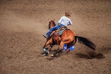 Cowgirl Riding Her Horse Around A Barrel In A Barrel Racing Competition. The Horse Is Kicking Up A Lot Of Dirt.