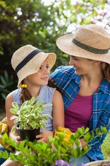 Wall Mural - Smiling mother with daughter holding potted plant