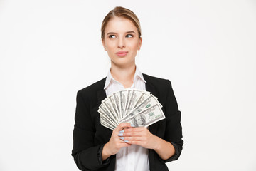 Wall Mural - Smiling pensive blonde business woman holding money and looking away