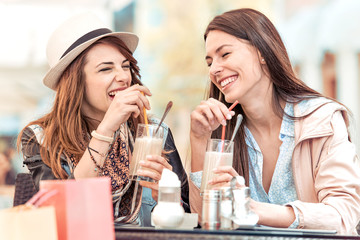 Two beautiful women drinking lemonade and chatting in cafe