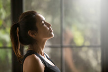 Profile Portrait Of Young Attractive Yogi Woman Breathing Fresh Air, Her Eyes Closed, Meditation Pose, Relaxation Exercise, Working Out Wearing Black Sportswear Top, Close Up Image, Window Background