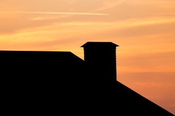 roof of a house with a chimney at sunset