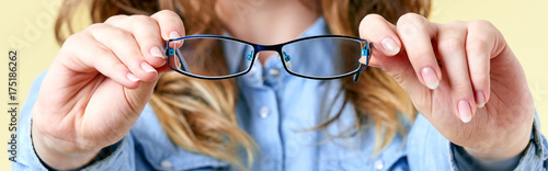 Cuadros en Lienzo Young woman with ginger hair holding reading glasses in front of her