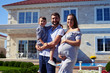 Happy family standing in front of new modern house