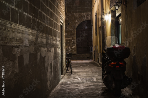 Plakat Motocyklu i roweru stojak w ciemnej alei przy nocą, Florencja, Włochy