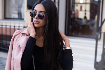 Wall Mural - Fashion close up portrait of pretty stylish woman in fall casual outfit walking in city. Street style.young beautiful stylish woman walking in street in pink coat,autumn fashion trend.