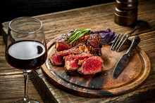 Grilled Ribeye Beef Steak With Red Wine, Herbs And Spices On Wooden Table