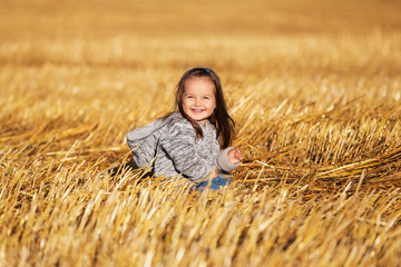 Happy 2 year old girl walking in a summer harvested field