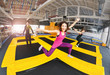 Cheerful and happy woman practicing and jumping on trampolines in a sports indoor center, workout and modern entertainment concept