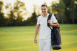© VadimGuzhva - A man in a white suit walks around the golf course with a golf club bag and smiles