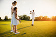 © VadimGuzhva - Great strike at sunset. The man hit the ball with a golf club. His family is behind and watching him