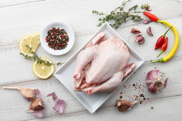 Cooking raw chicken with herbs and spices on white wooden background, top view