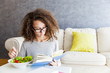 © BGStock72 - Curly hair teenage girl reading book and eating salad