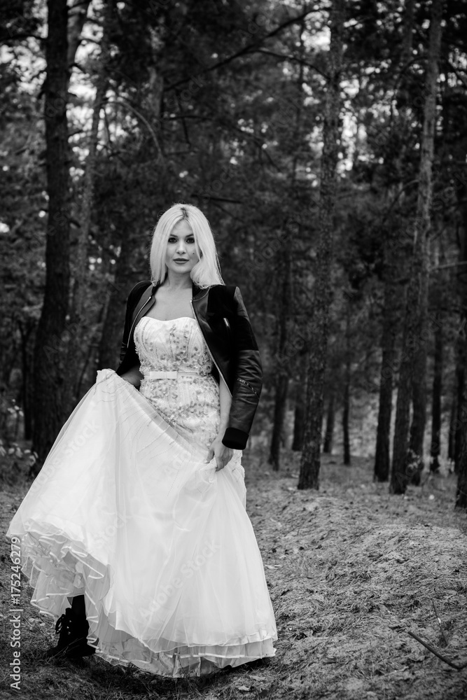 A runaway bride in a wedding dress and a leather jacket in the forest.  Difficulties at the wedding. Fashionable girl in grunge style Stock Photo |  Adobe Stock