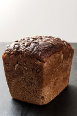 delicious fresh baked brown  bread with bran sunflower seeds on a dark background, vertical image