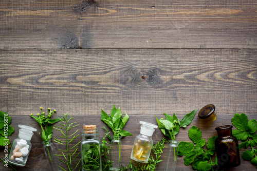 Zdjęcie XXL Homeopatia. Liście leczniczy ziele, butelki i pigułki na drewnianym tło odgórnego widoku copyspace ,.